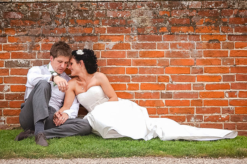Bride and Groom Sitting on the Grass Kissing