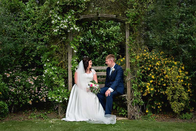 Bride and Groom Sitting on a Bench by teh Shrubs at Hungarian Hall
