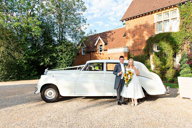 Bride and Groom Stand Next to the Rolls Royce outside Pontands Park Wedding Venue