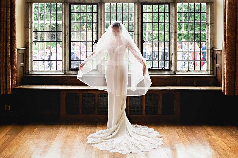 Bride With a Long Veil in front of teh Large Windows at Layey Marney Tower