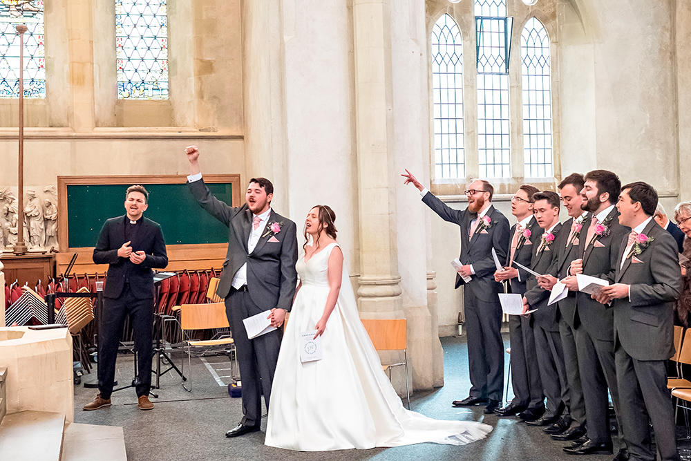 Christian Wedding Photographer | Bride and Groom Singing in Church with Arms Raised